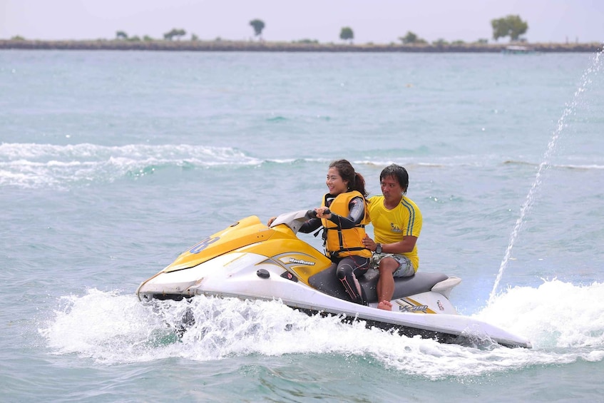 Two people on a jet ski with water splashing around them. 3