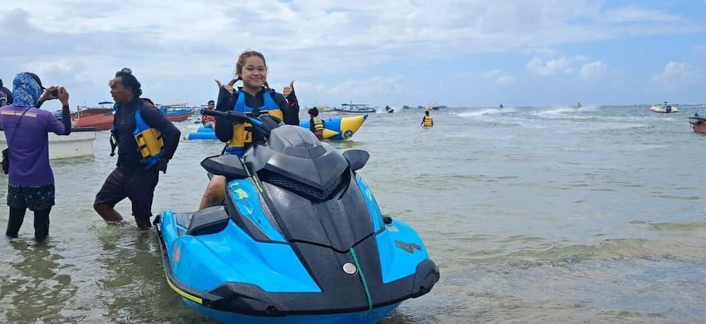 A person on a jet ski, another person taking a photo, and several boats in the background. 5
