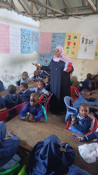 A classroom with children seated at desks, a teacher standing, and educational posters on the walls. 4