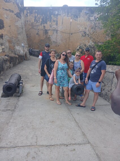 A group of people standing in front of a historical fortification with cannons. 1