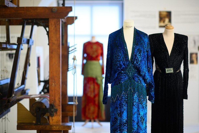 Mannequins in blue and black dresses, a sewing machine, and a mannequin in a red dress in the background. 5