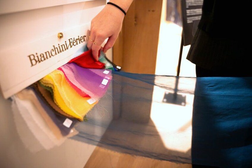 A hand reaching into a drawer labeled 'Bianchi Ferier' with various colored fabrics. 4