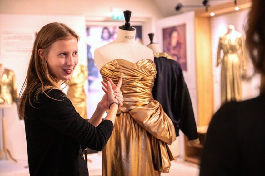 A person examining a golden dress on a mannequin in a store. 2