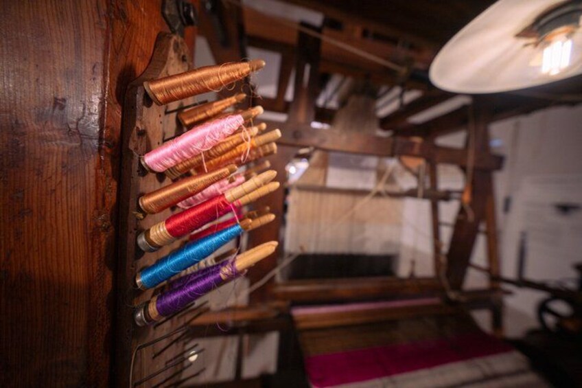 A wooden spinning wheel with colorful spools of thread. 3
