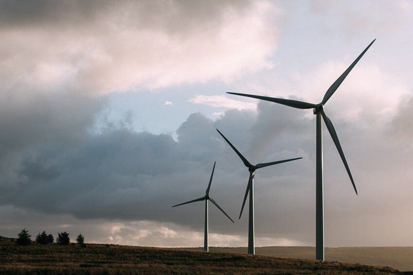 Three wind turbines on a hill under a cloudy sky. 4