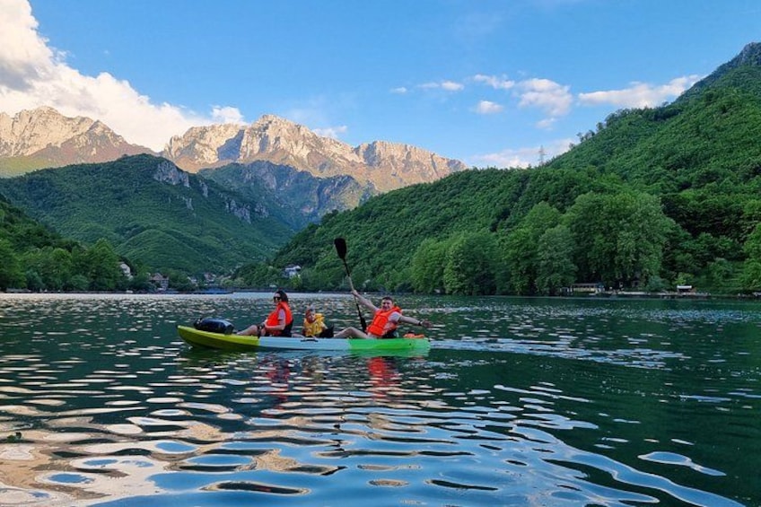 Two people kayaking on a calm lake with mountains in the background. 2