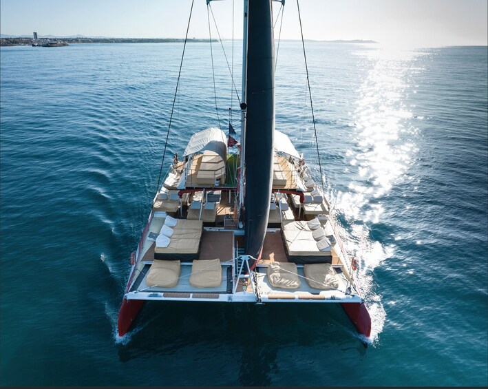 A sailboat with multiple deck chairs and a covered area, sailing on a calm sea. 3