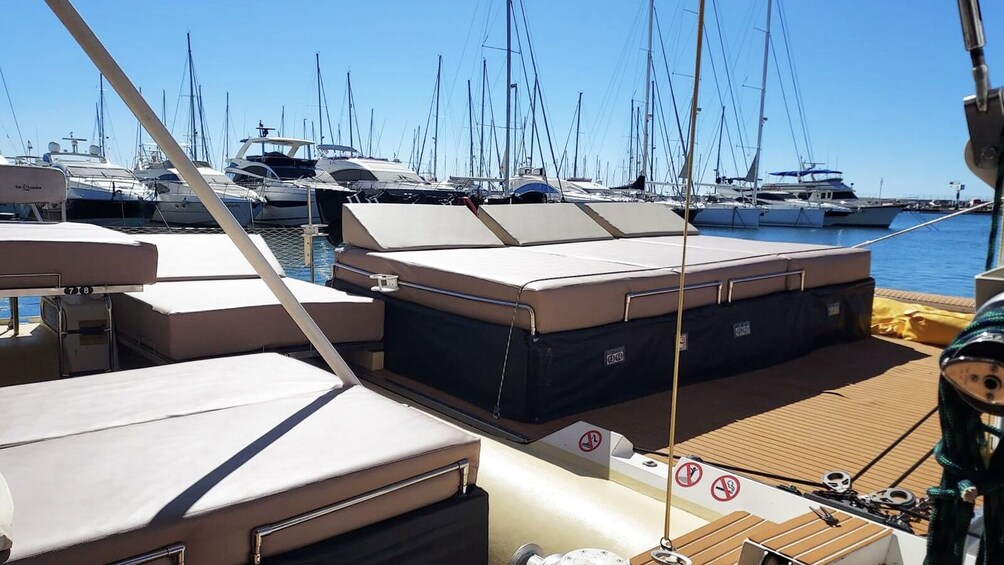 A marina with multiple yachts docked, a wooden deck, and a clear blue sky. 2
