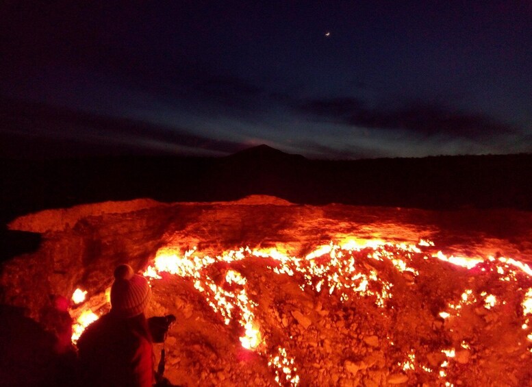 A lava field at night with glowing lava flows and a person observing. 3