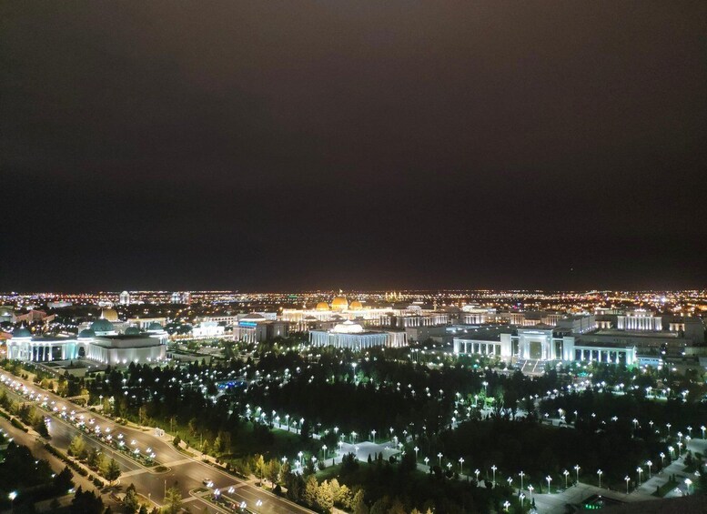 A cityscape at night with illuminated buildings and a large dome structure. 1
