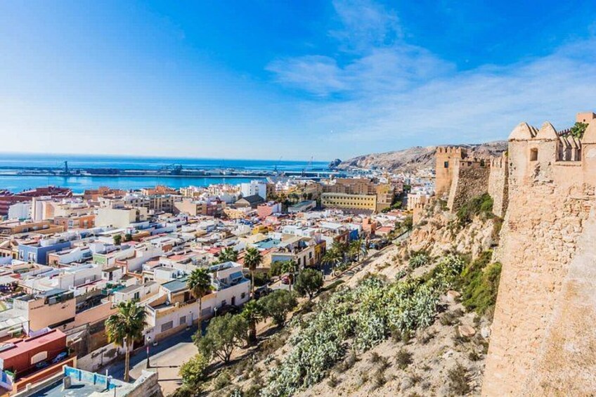 A coastal city with a historic fort, dense urban area, and a clear blue sky. 1