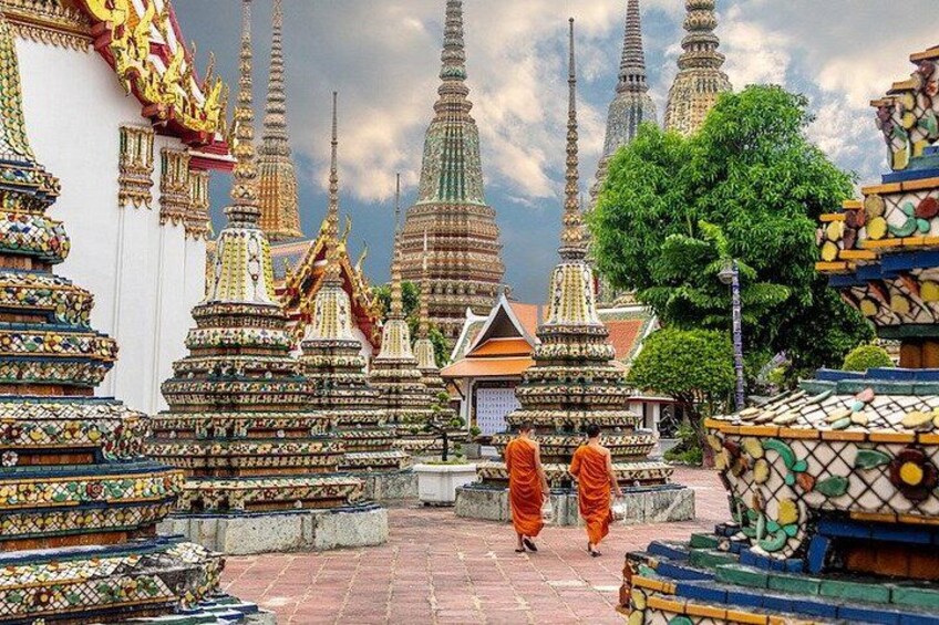 A temple complex with ornate structures and a monk walking. 2