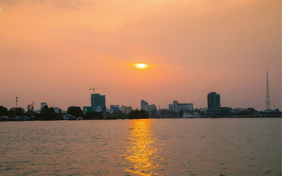 A sunset over a city skyline with buildings and a river reflecting the sun. 4