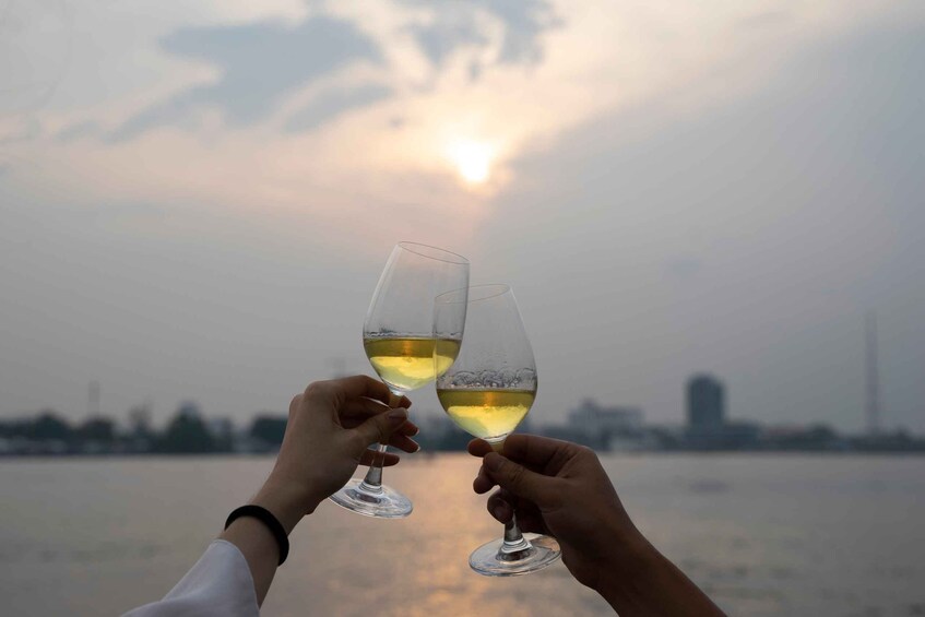 Two people toasting with wine glasses against a sunset over a body of water. 2