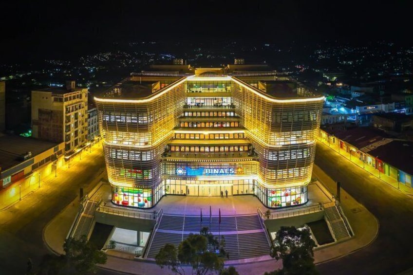 A modern building with illuminated signage, surrounded by a well-lit urban area at night. 1