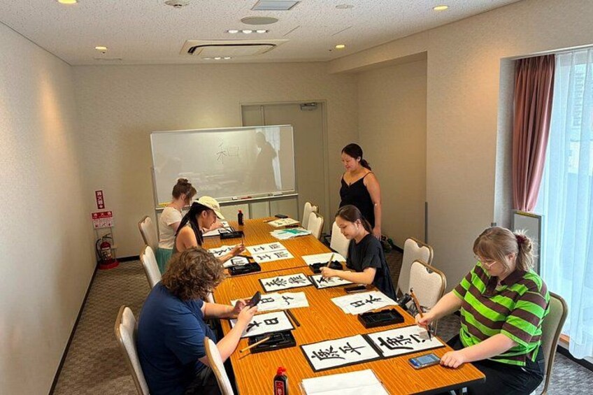 A conference room with a long table, people seated, and a whiteboard in the background. 2