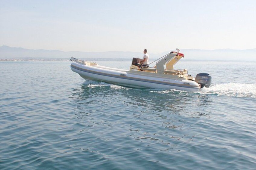 A small motorboat on calm water with a person steering it. 2