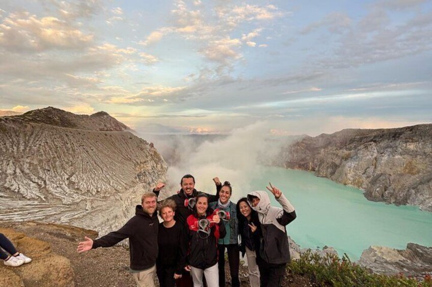 A group of people standing on a rocky outcrop with a turquoise river and mountains in the background. 5