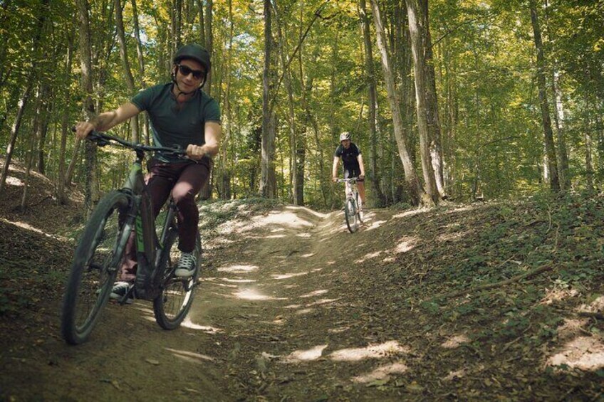 Two cyclists on a dirt trail surrounded by trees. 5