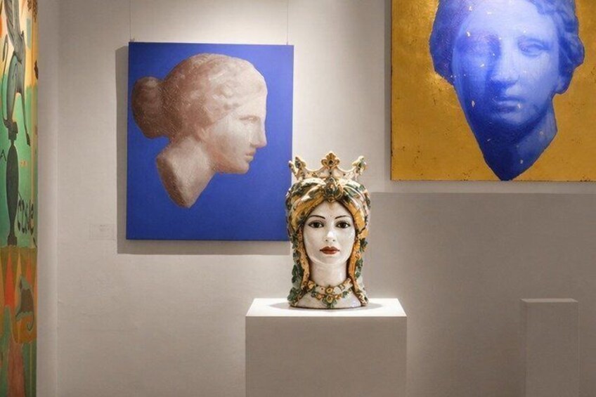 A bust sculpture on a pedestal, a blue painting with a classical figure, and a golden painting with a blue figure. 1