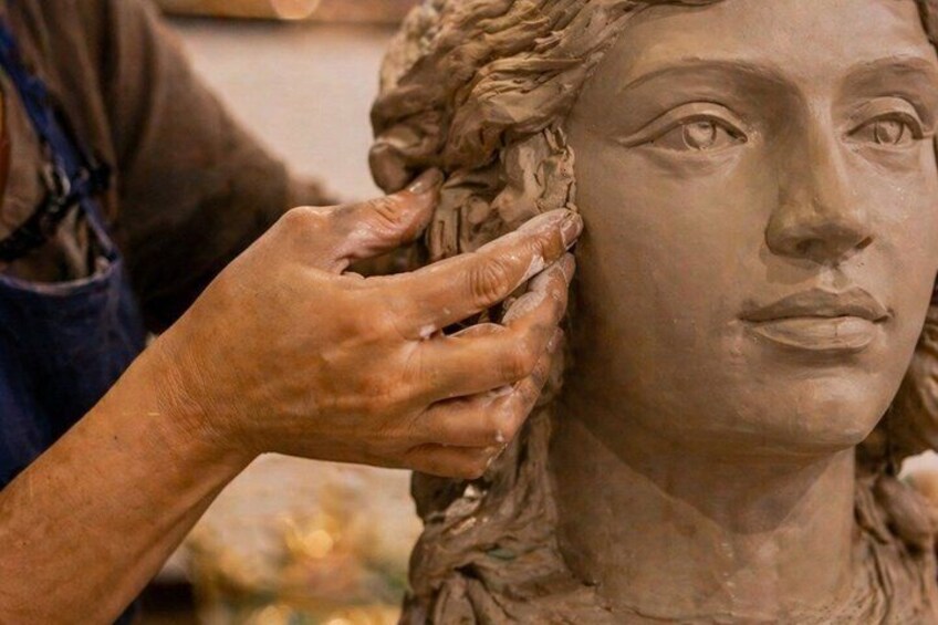 A sculptor working on a detailed bust, focusing on the hair texture. 3