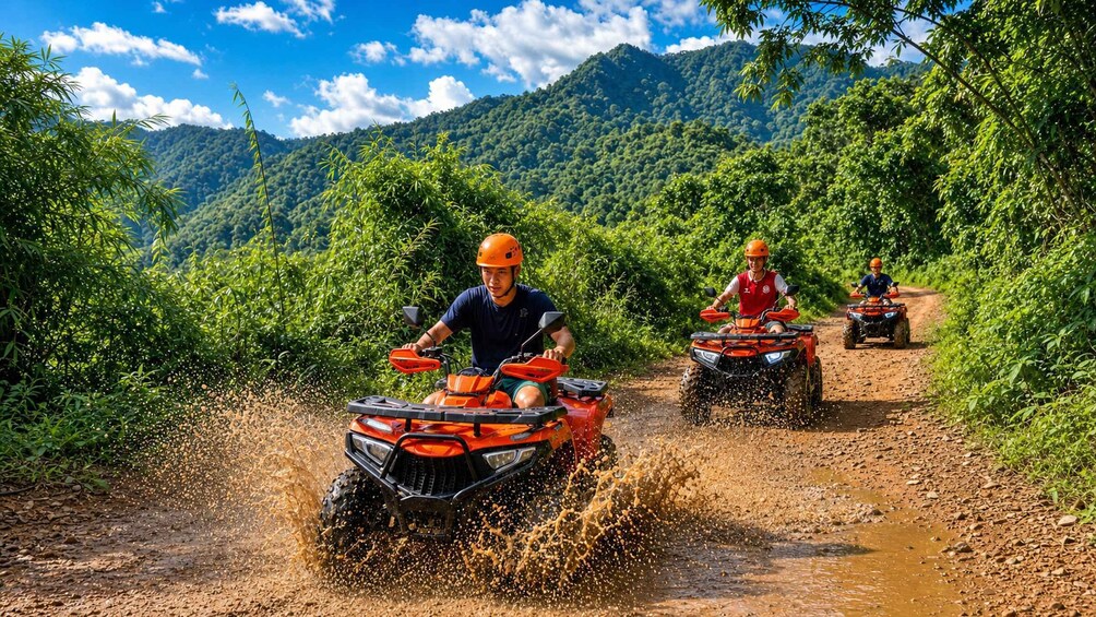 Three people riding ATVs on a muddy trail surrounded by lush greenery and mountains. 1