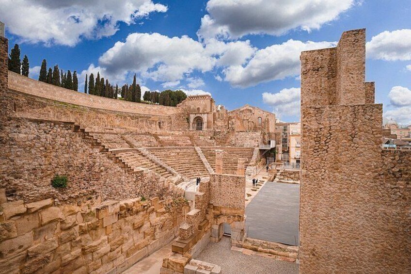 Ancient stone ruins with a large amphitheater, steps, and a clear sky. 4
