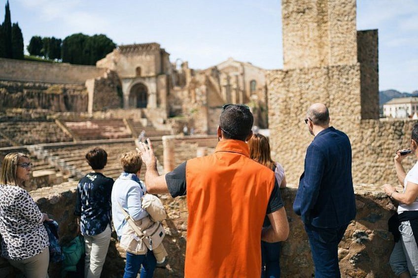 Tourists at an ancient archaeological site with ruins and a tall stone structure. 1