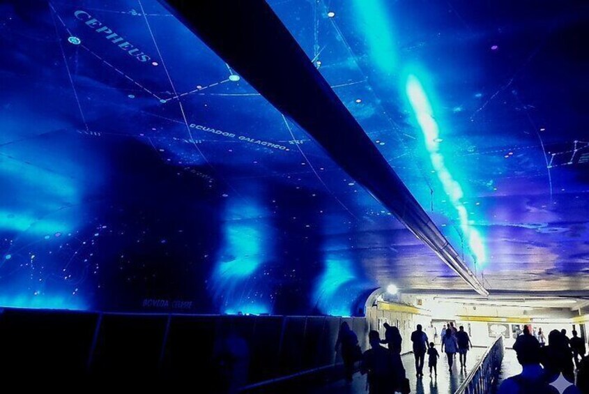 A subway station with digital displays and a crowd of people. 3