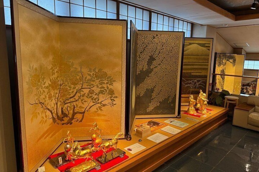 A traditional Japanese room with tatami flooring, a low table with golden statues, and sliding doors with nature scenes. 5