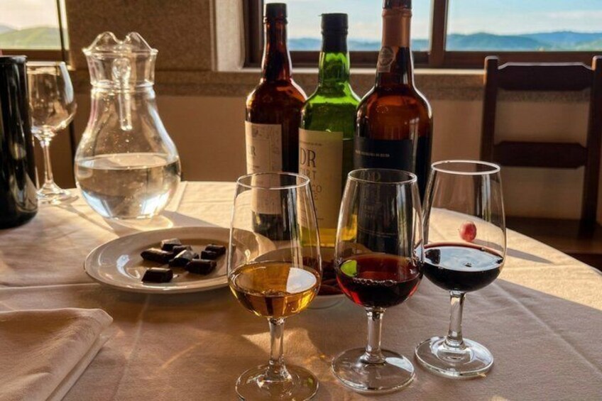 A table with wine glasses, bottles, a pitcher, and a plate of chocolates. 4