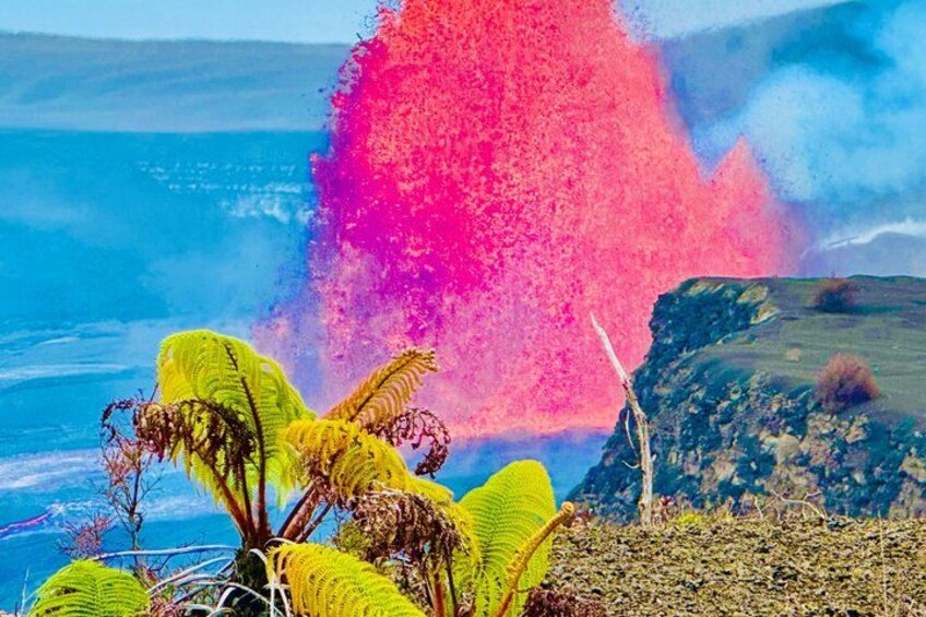 A coastal landscape with a large splash of pink and blue water, green foliage, and a rocky outcrop. 1
