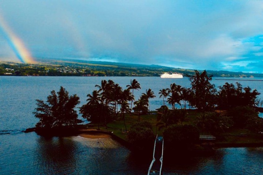A tropical island with a rainbow, palm trees, and a boat on the water. 2