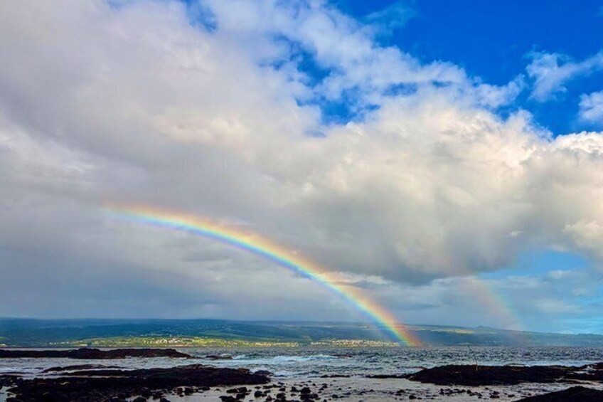 A rainbow over a coastal landscape with clouds. 4