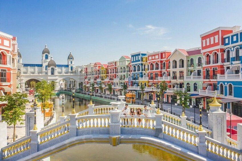 A colorful street with a bridge, buildings, and a canal. 1