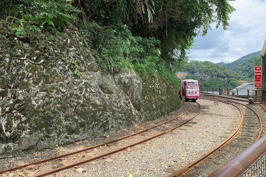 A train on a curved track surrounded by greenery and a mountainous landscape. 3