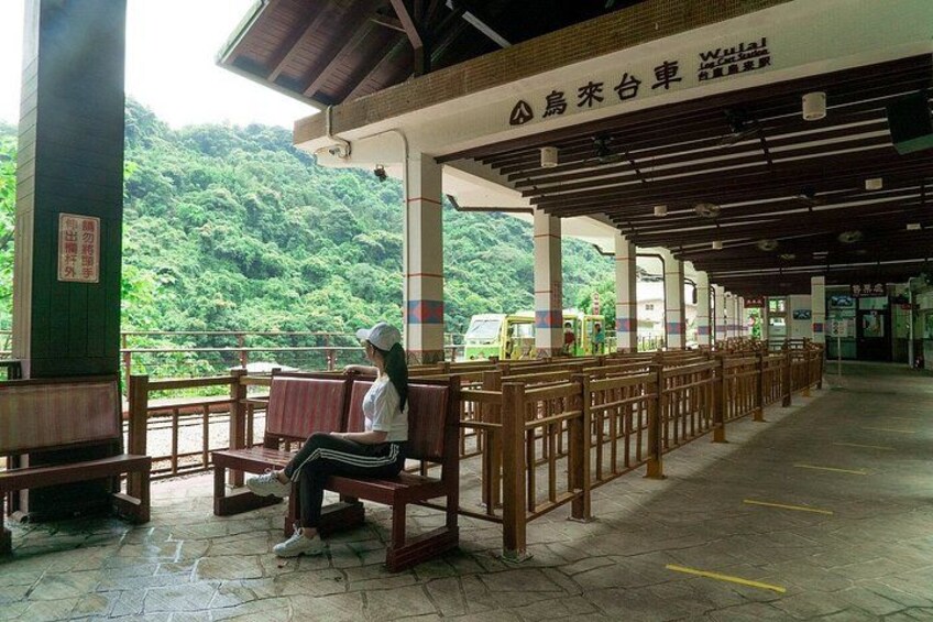 A covered waiting area with benches and a view of a forested hill. 4