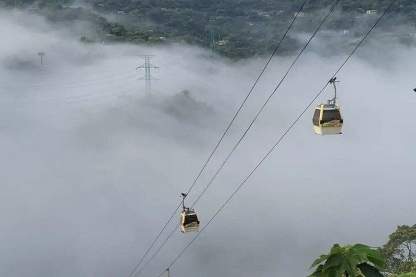 Two cable cars suspended above a misty landscape with power lines. 5