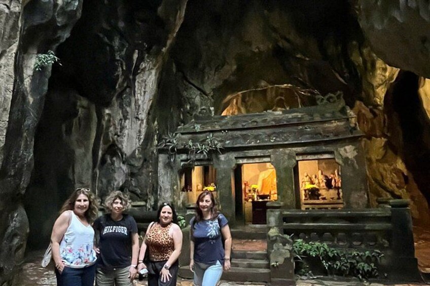 A group of people standing in front of a cave-like structure with a small building inside. 4