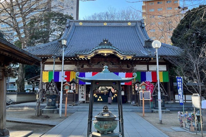 A traditional Japanese building with a tiled roof, surrounded by colorful flags and a lantern in the foreground. 3