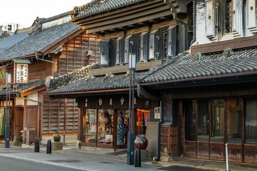 A traditional Japanese street with wooden buildings, tiled roofs, and a clear sky. 4
