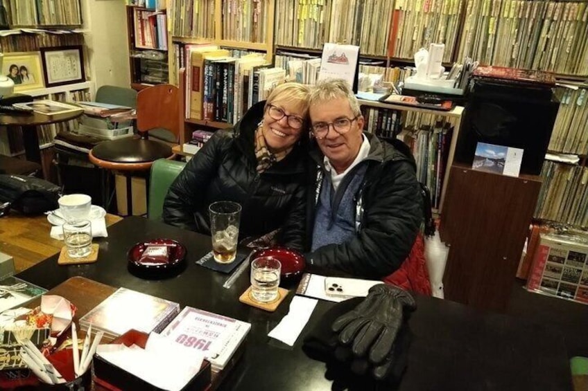 Two people sitting at a table in a bookstore with bookshelves in the background. 4