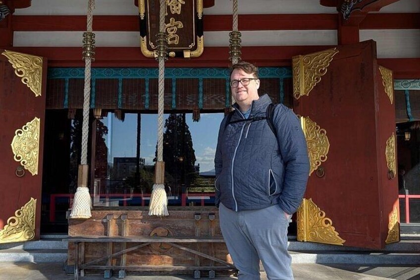 A person standing in front of a traditional building with ornate decorations and a wooden structure. 3