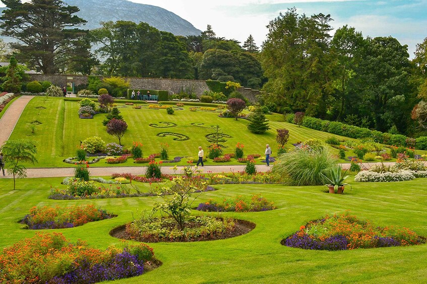 A well-manicured garden with circular flower beds, a pathway, and a stone wall. 5