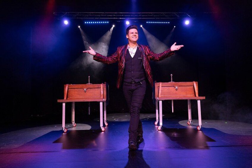 A person on stage with two wooden boxes and spotlights. 2