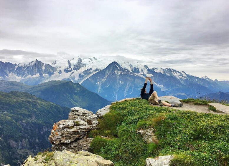 A person sitting on a mountain ridge with a view of snow-capped peaks. 3
