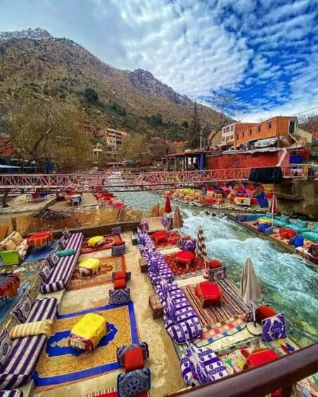 A riverside setting with colorful seating arrangements and a bridge in the background. 5