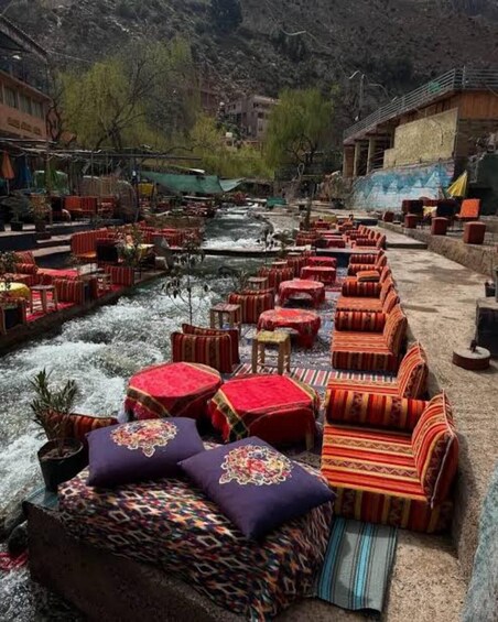 Outdoor seating by a river with colorful cushions and a mountainous backdrop. 4