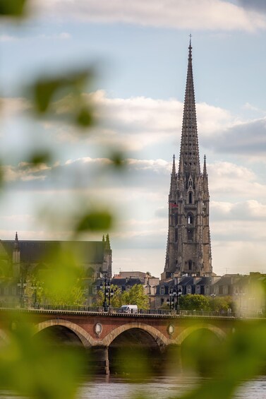 A cathedral with a tall spire, a bridge, and a river. 5