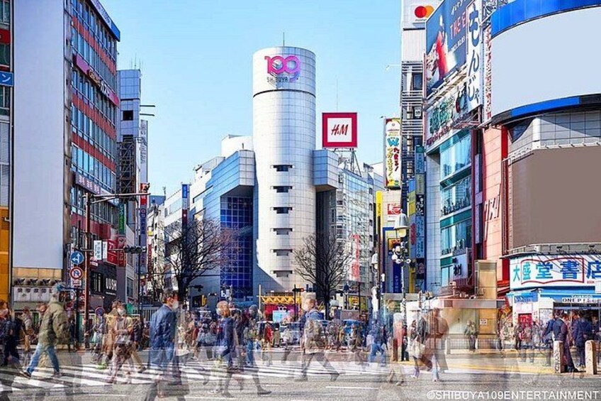 A busy urban street with modern buildings, a prominent cylindrical structure, and various commercial signs. 2